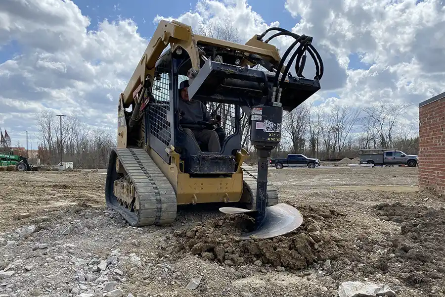 A Bobcat compact loader using an auger attachment to drill a hole on a residential construction site in New Albany, Ohio.